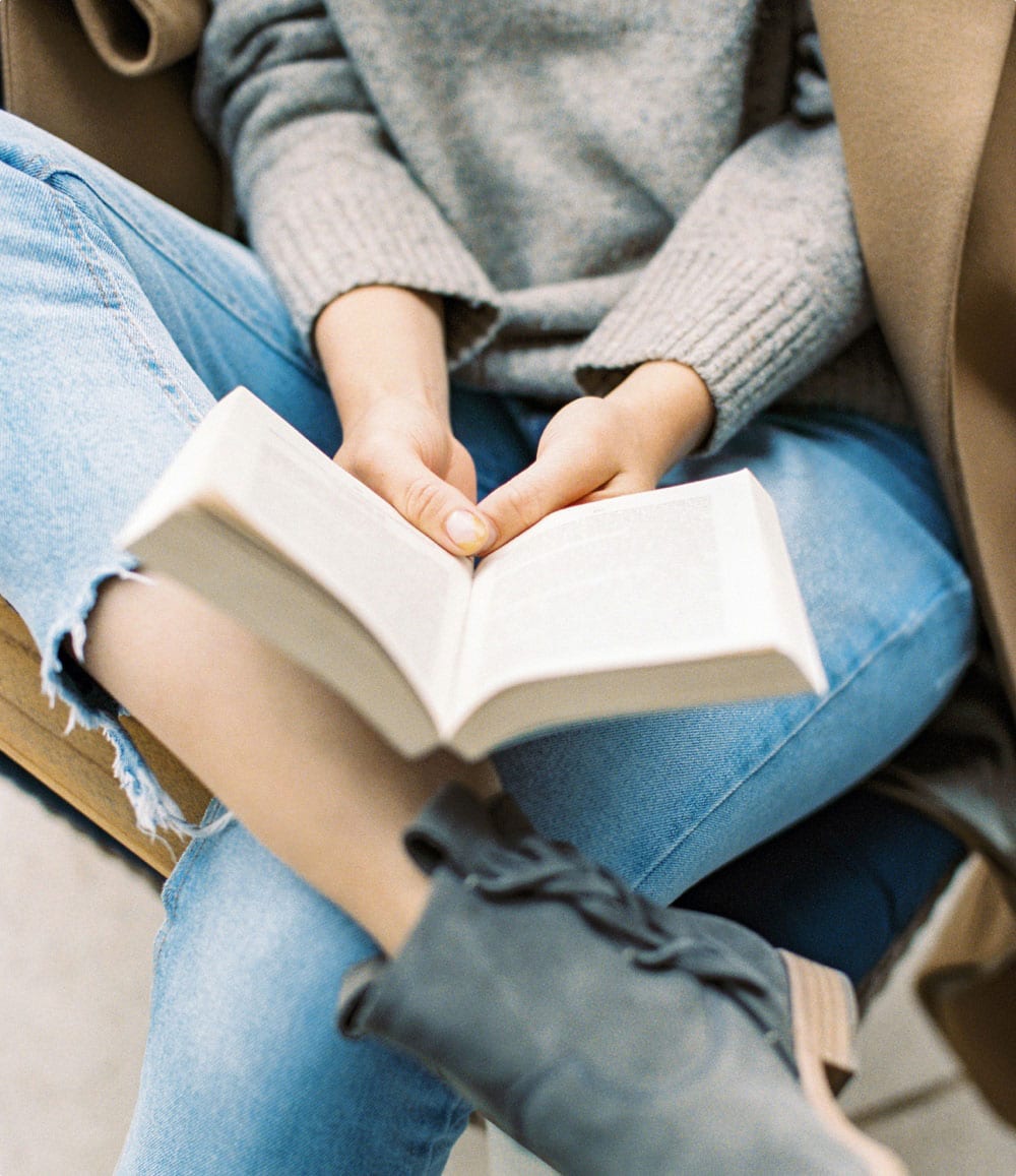 A resident reads a book with her legs crossed at the Ora Seaport Apartments in Boston